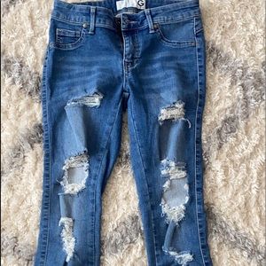 Guess blue jeans with rips and cuffed ankle.